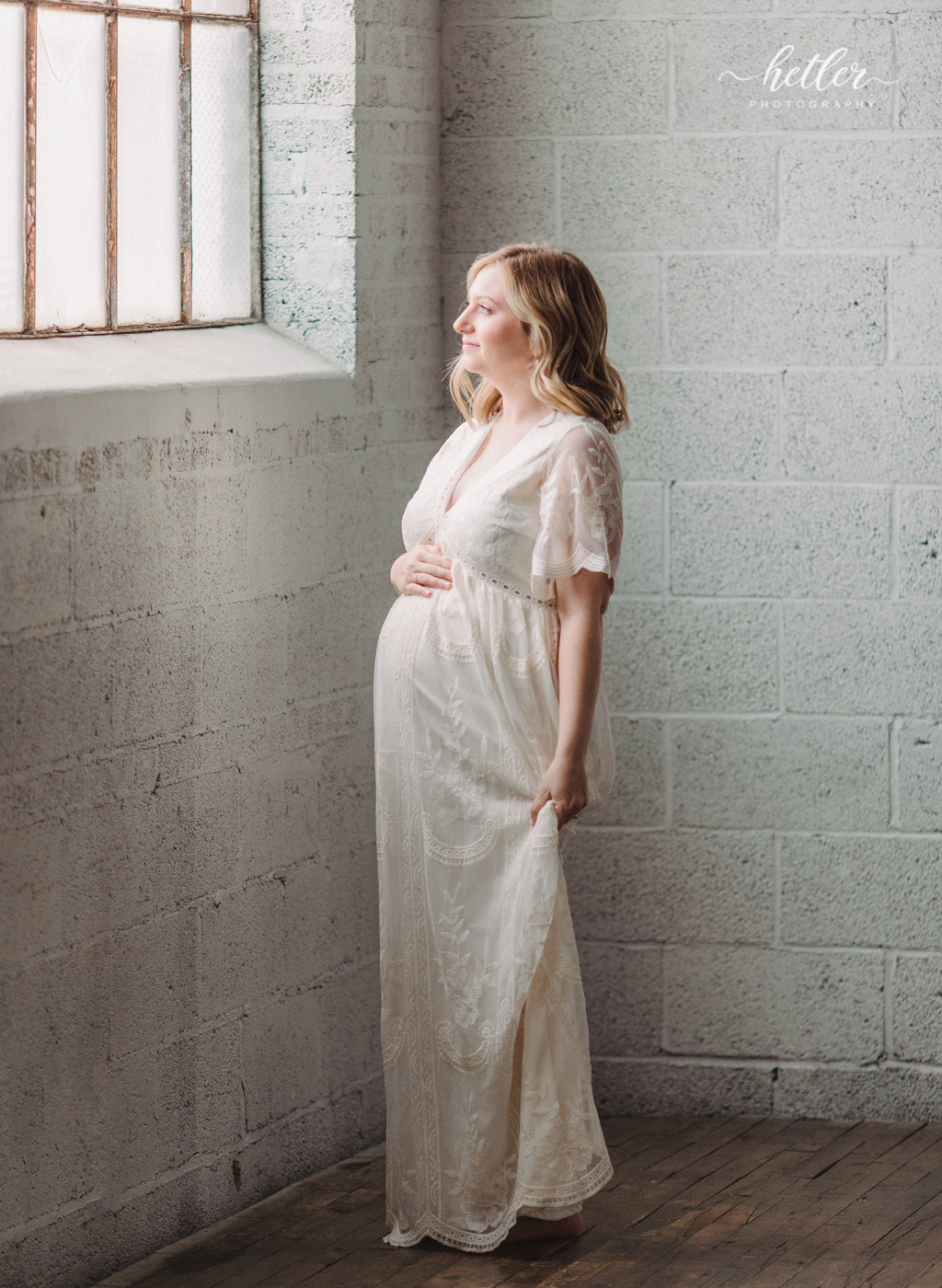 Grand Rapids maternity photos at a natural light studio with mom in a beautiful white dress
