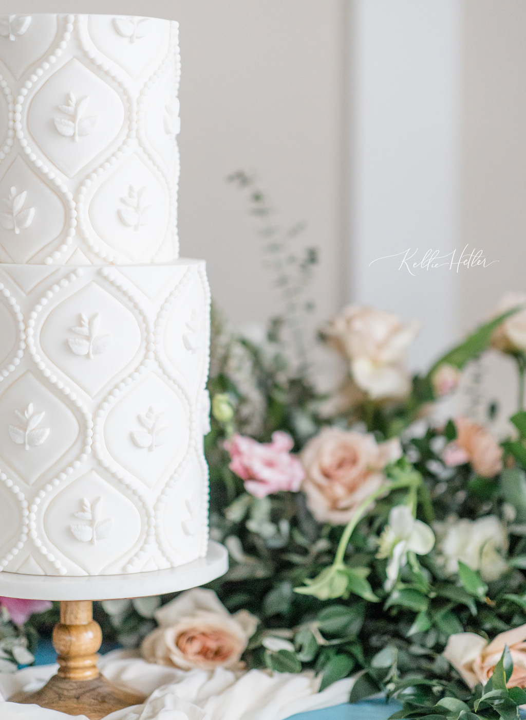 Intricate floral pattern on all white wedding cake