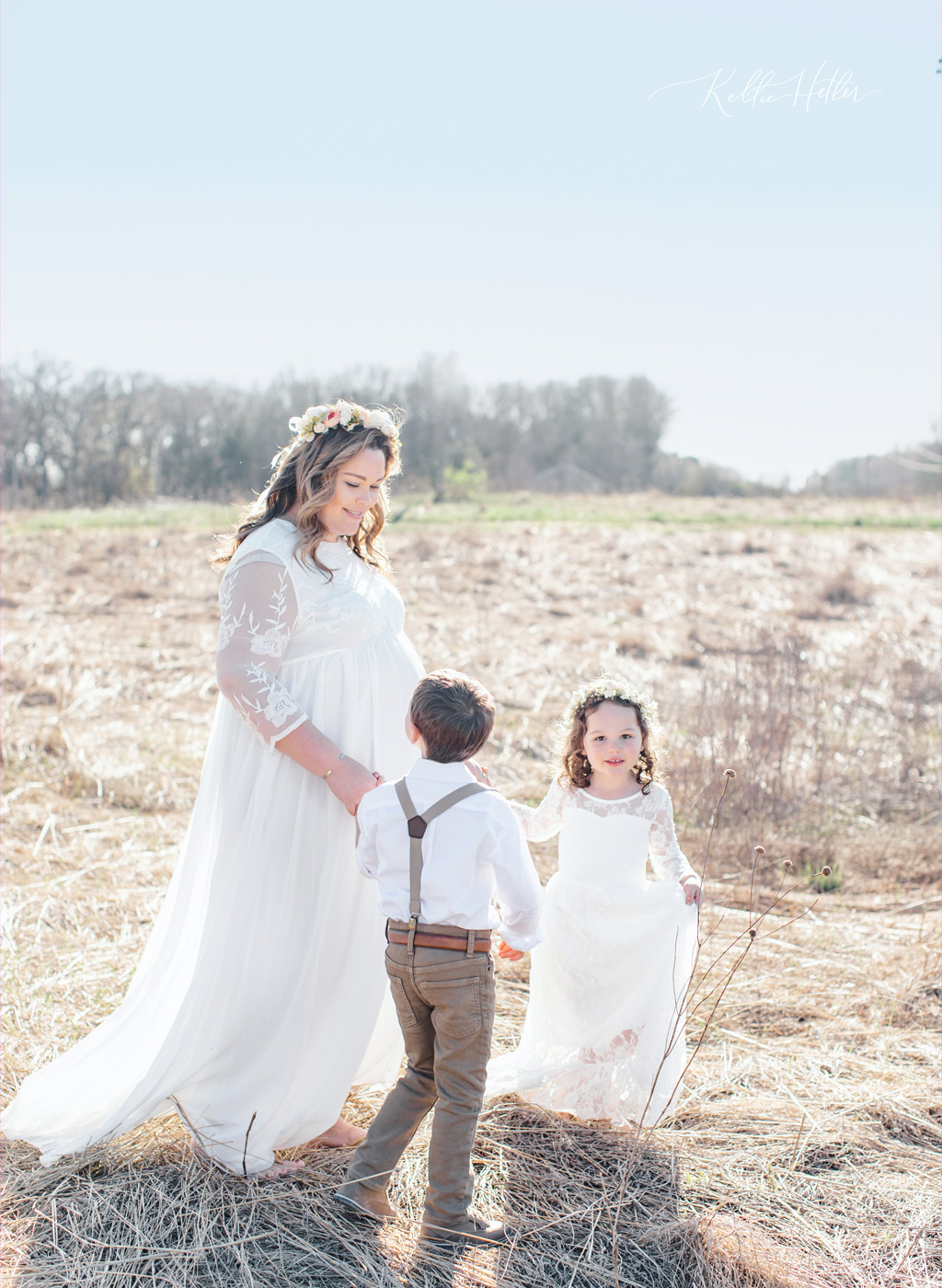 Expectant mom with kids in field with white dress