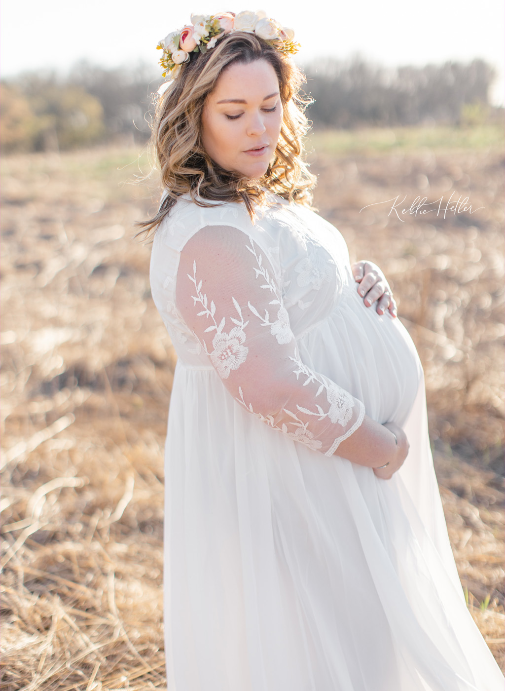 Pregnant mom in a field in a white gown and floral crown