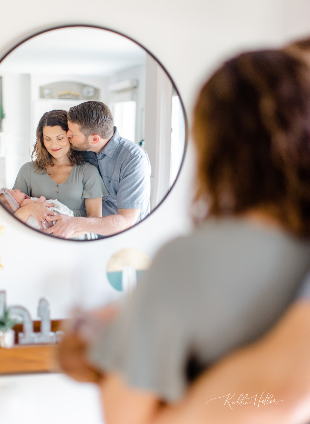 parents cuddling baby girl in reflection of mirror