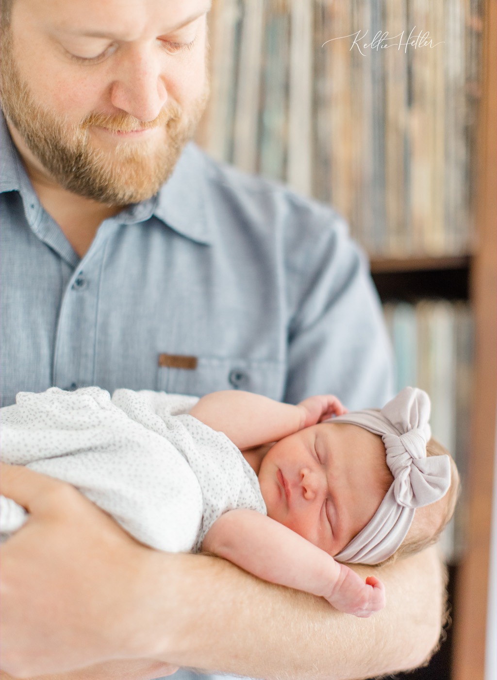 dad holding newborn baby in front of old records